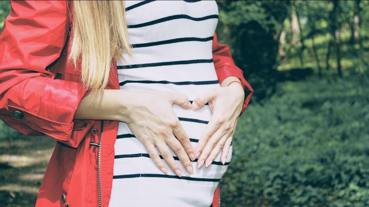 woman forming heart on her womb during daytime